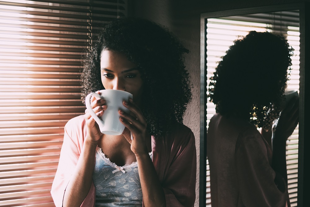 Woman sipping coffee by the window, contemplating life